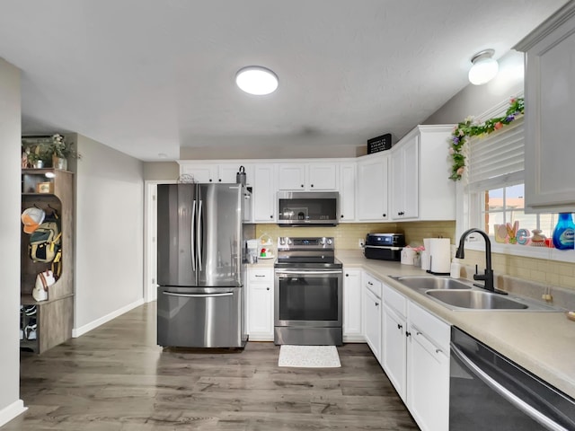 kitchen with stainless steel appliances, a sink, tasteful backsplash, wood finished floors, and light countertops