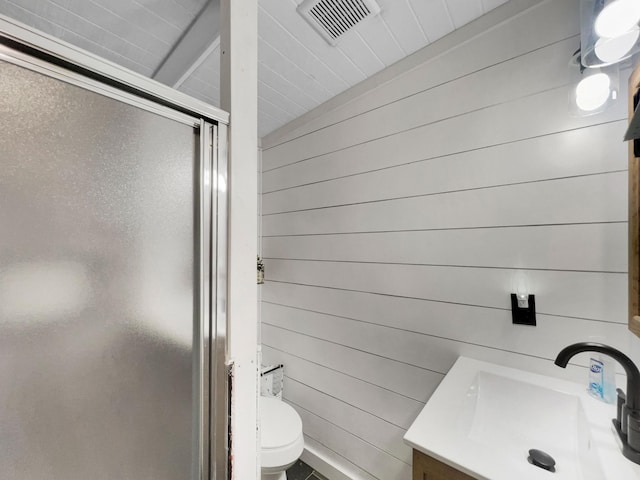 bathroom with wood walls, vanity, a shower stall, and visible vents