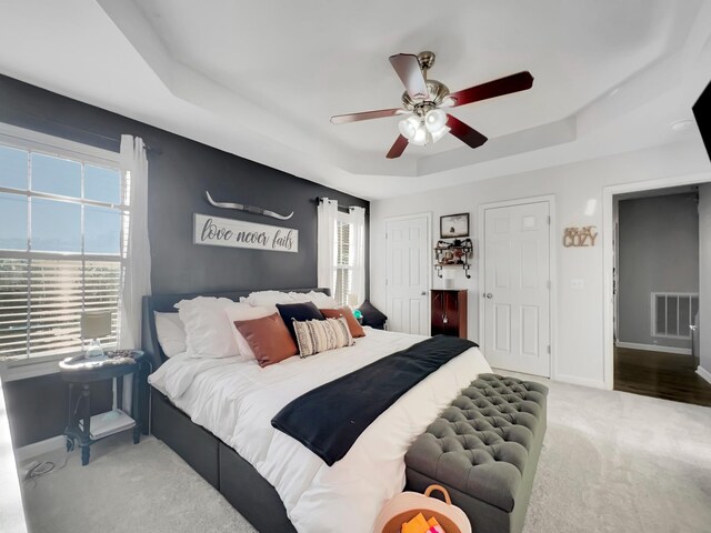 bedroom with visible vents, baseboards, carpet flooring, and a raised ceiling