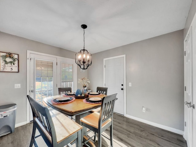 dining area featuring dark wood-style flooring, baseboards, and a notable chandelier