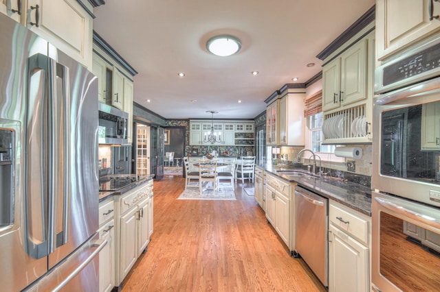 1143 Carnton Ln, Franklin, TN 37064 - kitchen with dark stone countertops, decorative backsplash, stainless steel appliances, light wood finished floors, and a sink