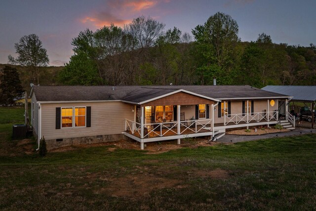 back of property at dusk featuring crawl space, a yard, covered porch, and central air condition unit