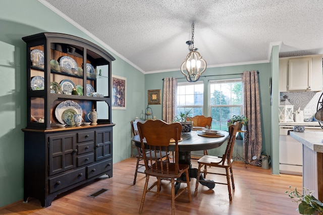 dining area featuring crown molding, light wood-style floors, a textured ceiling, visible vents, and a chandelier