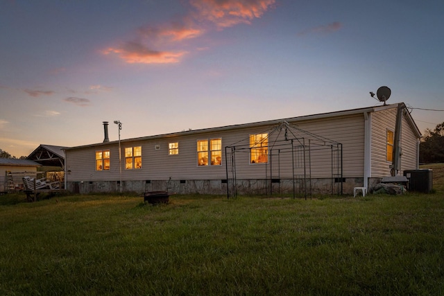 back of property featuring a lawn and crawl space
