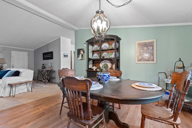 dining area featuring a notable chandelier, light wood-style flooring, a textured ceiling, and lofted ceiling