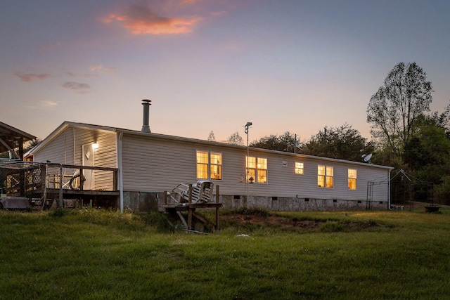 rear view of property with crawl space, a deck, and a lawn