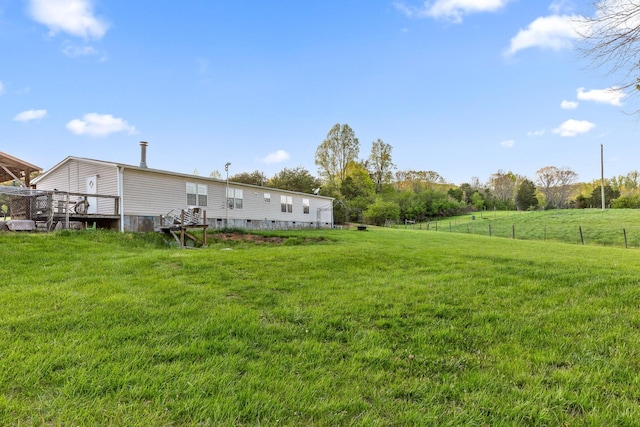 view of yard featuring a deck, a rural view, and fence