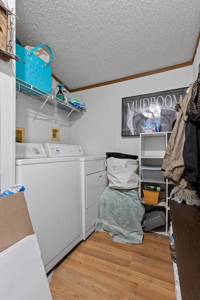 washroom featuring ornamental molding, laundry area, a textured ceiling, light wood-style flooring, and washing machine and dryer