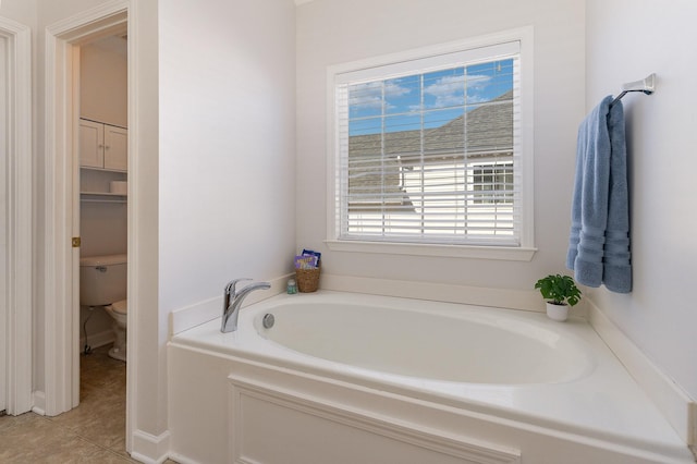 bathroom featuring toilet, a bath, and tile patterned flooring