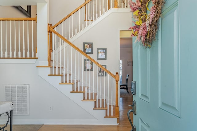 stairway featuring wood finished floors, baseboards, and visible vents