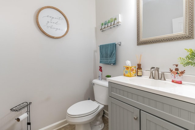 bathroom featuring toilet, vanity, and baseboards