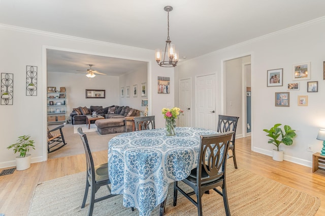 dining area with crown molding, ceiling fan with notable chandelier, light wood finished floors, and baseboards