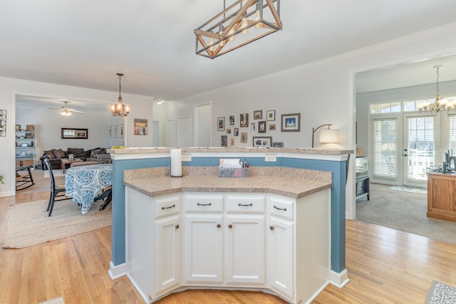 kitchen with pendant lighting, ornamental molding, white cabinets, a kitchen island, and open floor plan