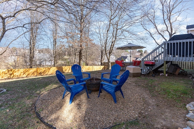 view of yard with an outdoor fire pit, a fenced backyard, a wooden deck, and stairway