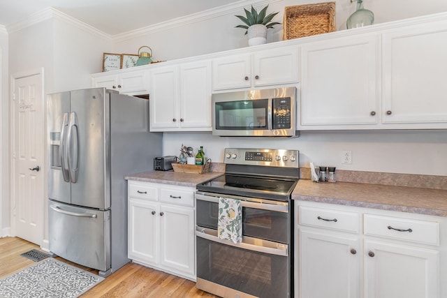 kitchen featuring light wood-style flooring, light countertops, crown molding, white cabinets, and appliances with stainless steel finishes