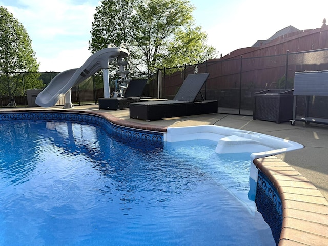 view of pool featuring a patio area, a water slide, a fenced in pool, and fence