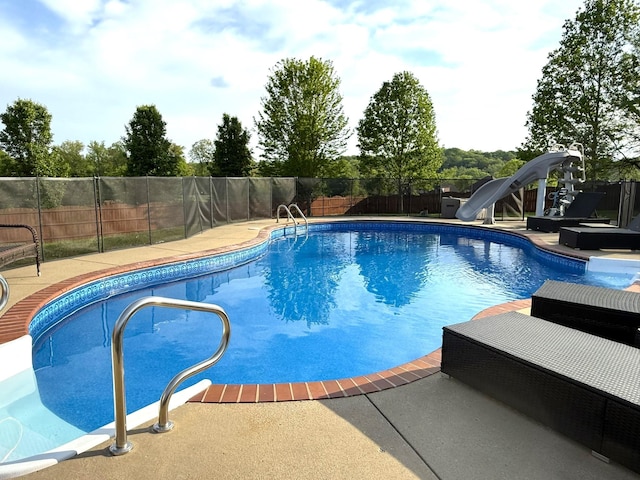 view of swimming pool featuring fence, a patio area, a fenced in pool, and a water slide