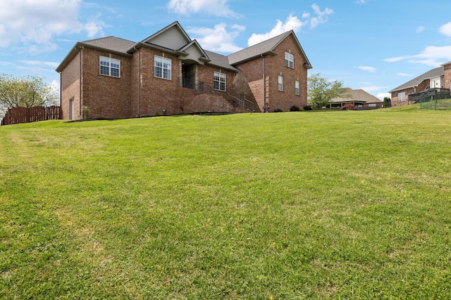 exterior space with brick siding, a front lawn, and fence
