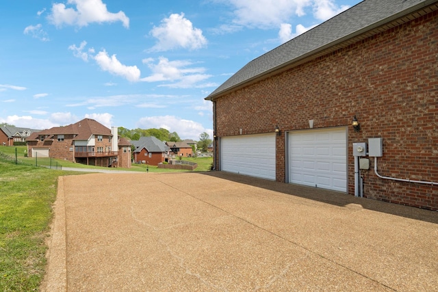 view of side of home with a garage, brick siding, a residential view, and concrete driveway