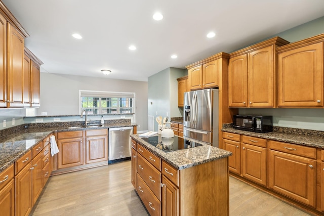 kitchen with black appliances, brown cabinets, a sink, and light wood-style floors