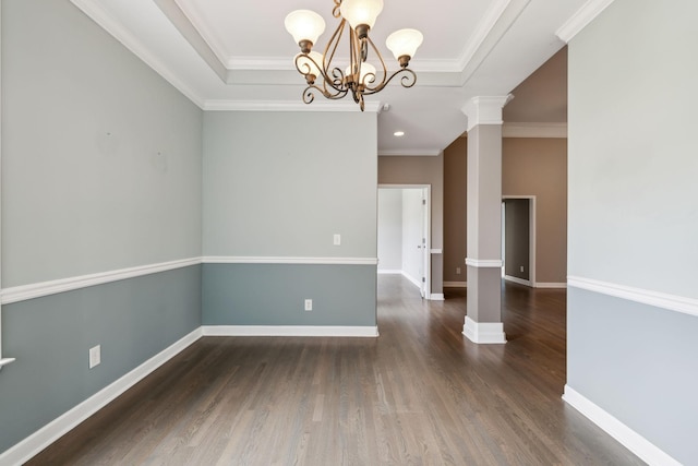 spare room featuring ornate columns, wood finished floors, ornamental molding, baseboards, and a chandelier