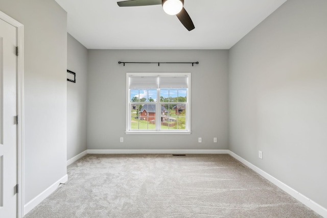 carpeted spare room featuring a ceiling fan and baseboards