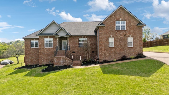 view of front of house featuring fence, brick siding, a front yard, and roof with shingles