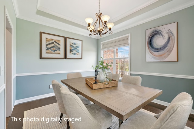 dining area featuring crown molding, wood finished floors, a tray ceiling, baseboards, and a notable chandelier