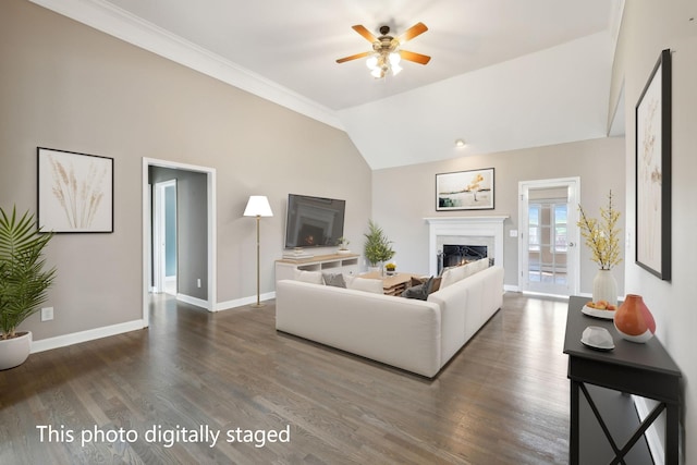 living room with dark wood finished floors, vaulted ceiling, baseboards, ceiling fan, and a lit fireplace