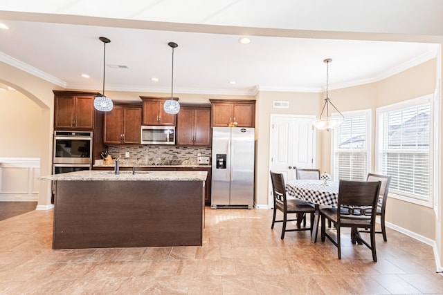 133 Kildeer Dr, Clarksville, TN 37040 - kitchen featuring arched walkways, a sink, a kitchen island with sink, light stone countertops, and stainless steel appliances