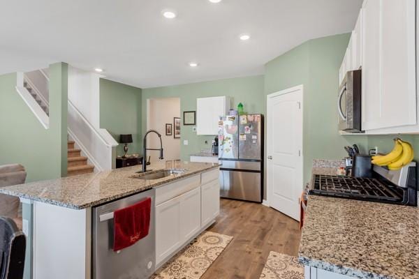kitchen with a sink, light wood-style floors, a center island with sink, appliances with stainless steel finishes, and white cabinetry