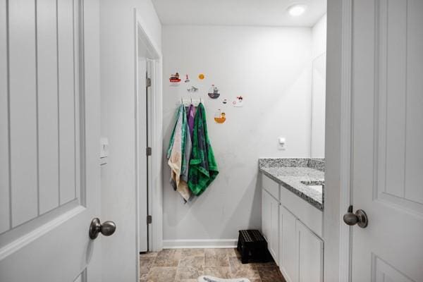 bathroom featuring stone finish flooring, baseboards, and vanity