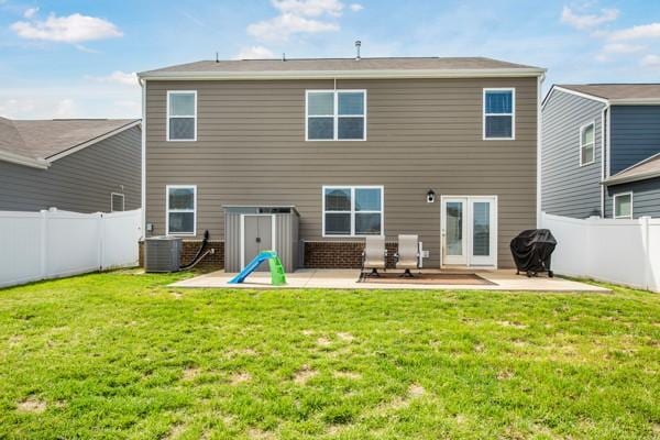 rear view of house with cooling unit, a yard, a patio area, and a fenced backyard