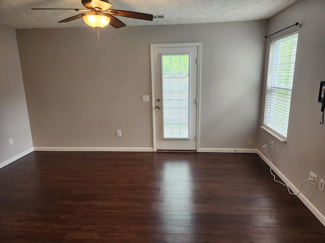 unfurnished room with ceiling fan, dark wood-style flooring, a textured ceiling, and visible vents