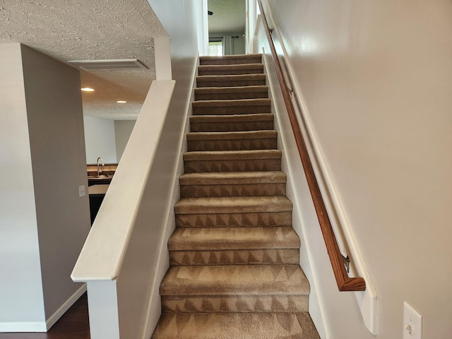 staircase with visible vents, wood finished floors, baseboards, recessed lighting, and a textured ceiling