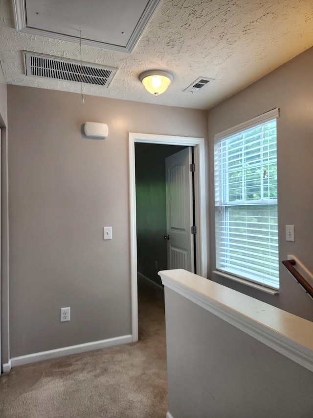 corridor featuring carpet, baseboards, visible vents, and attic access