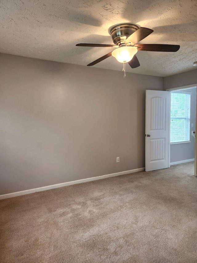 spare room featuring light carpet, baseboards, and a ceiling fan