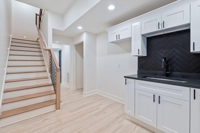 416 Mercomatic Dr, Nashville, TN 37209 - kitchen with tasteful backsplash, light wood-type flooring, white cabinetry, dark countertops, and a sink
