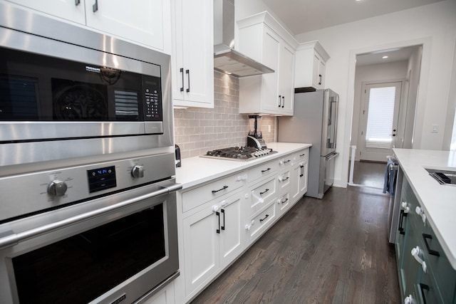 3509B Wrenwood Ave, Nashville, TN 37205 - kitchen featuring wall chimney range hood, light countertops, backsplash, dark wood-type flooring, and appliances with stainless steel finishes