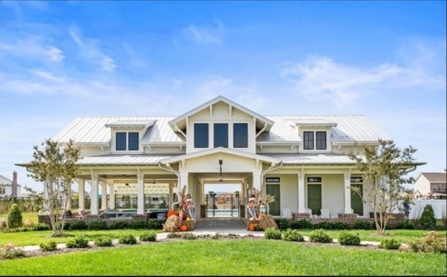 back of property featuring a porch, a yard, and metal roof