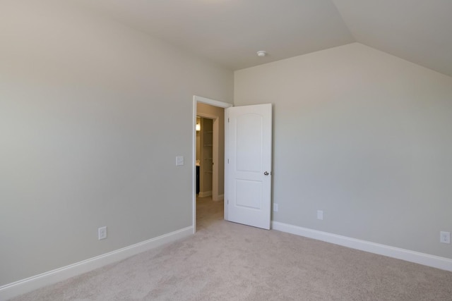 empty room with light carpet, baseboards, and lofted ceiling