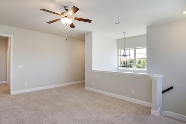 unfurnished room featuring carpet, visible vents, ceiling fan with notable chandelier, and baseboards