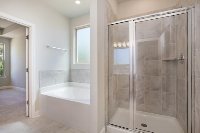 bathroom featuring tile patterned flooring, a bath, baseboards, and a stall shower