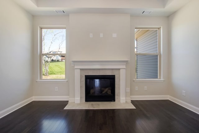 unfurnished living room with wood finished floors, a tiled fireplace, visible vents, and plenty of natural light
