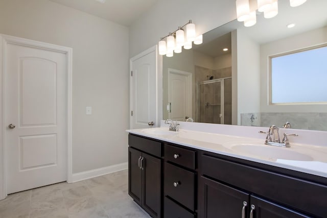 bathroom featuring a shower stall, double vanity, a sink, and baseboards