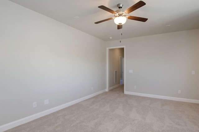 spare room with baseboards, ceiling fan, and light carpet