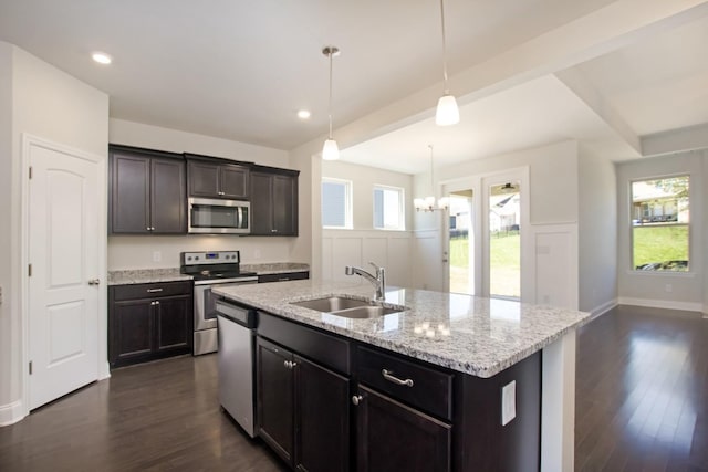 kitchen featuring a sink, dark wood finished floors, light stone countertops, and stainless steel appliances