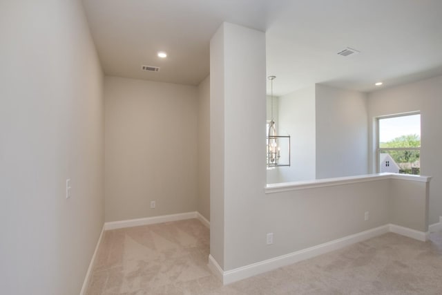 empty room with visible vents, baseboards, an inviting chandelier, and carpet