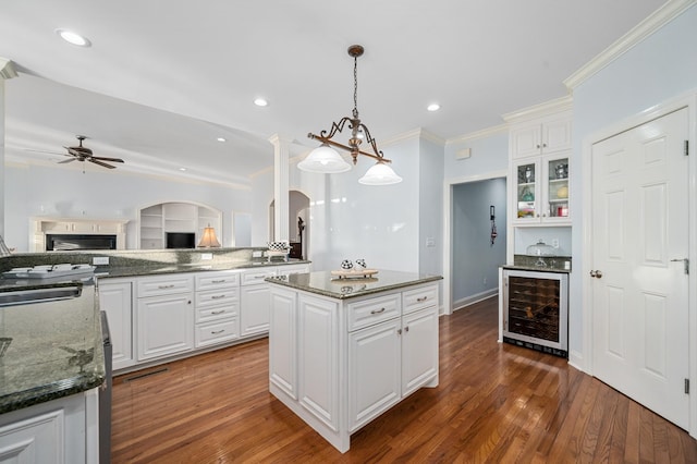 kitchen featuring white cabinets, a kitchen island, a ceiling fan, and wine cooler