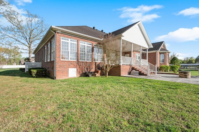 view of front of house with brick siding, a front lawn, and covered porch
